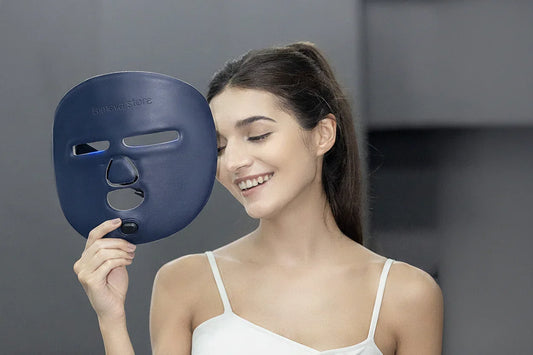 Smiling woman holding navy blue Lumeva Store LED face mask for skincare treatment
